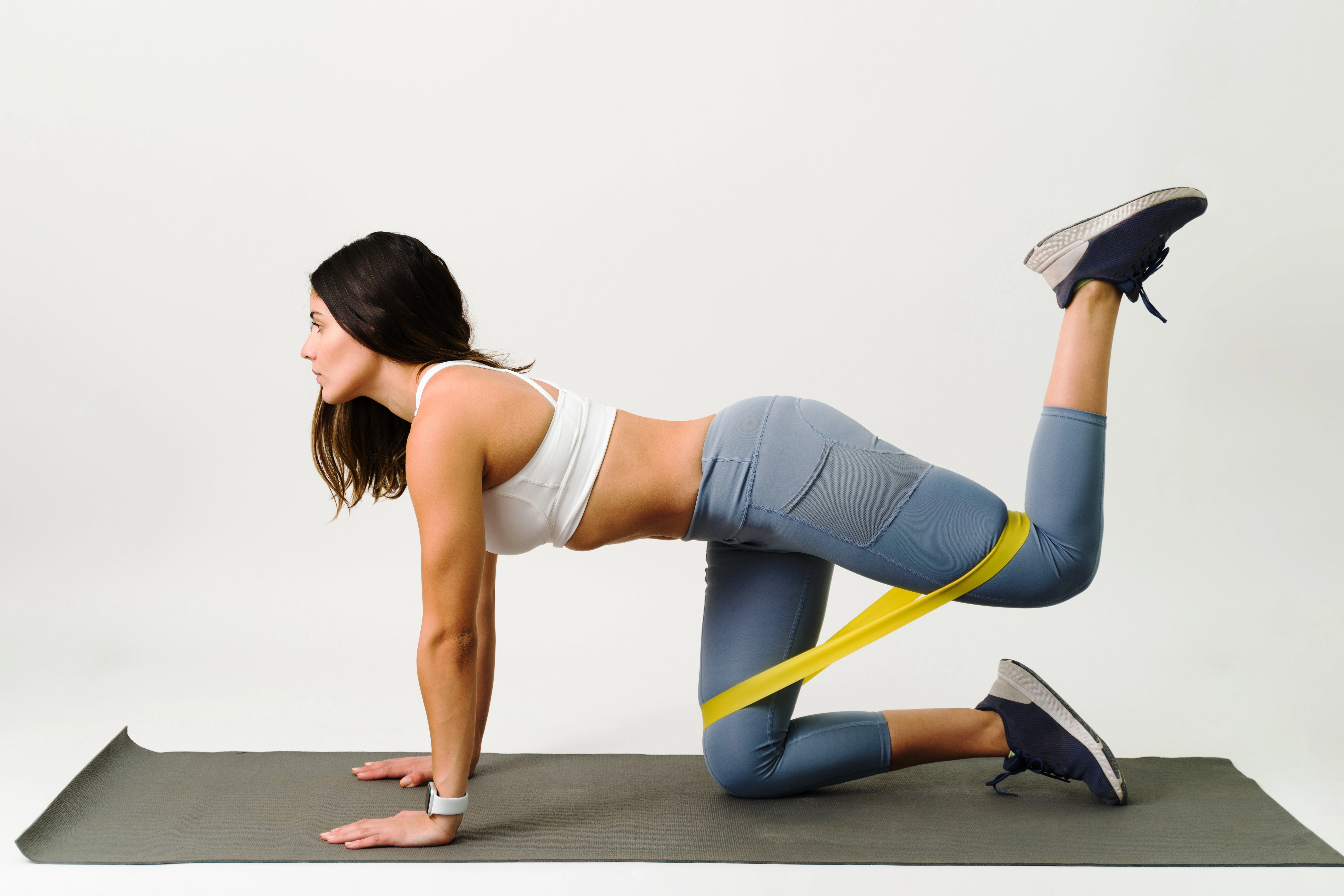 attractive-young-woman-activewear-working-out-exercise-mat-doing-kickback-exercises-with-resistance-