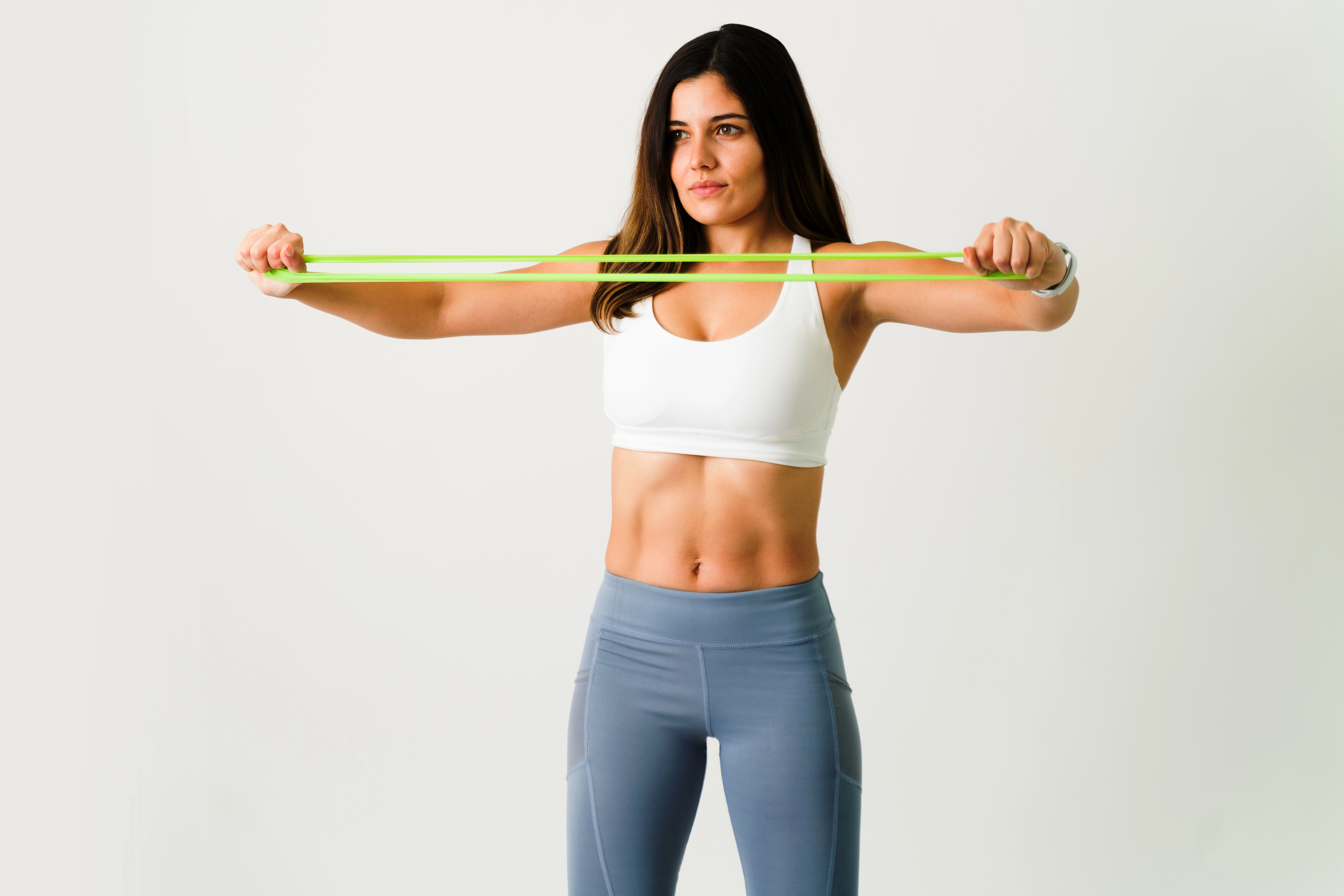 fitness-woman-with-healthy-lifestyle-using-yellow-resistance-band-during-workout-session-against-whi