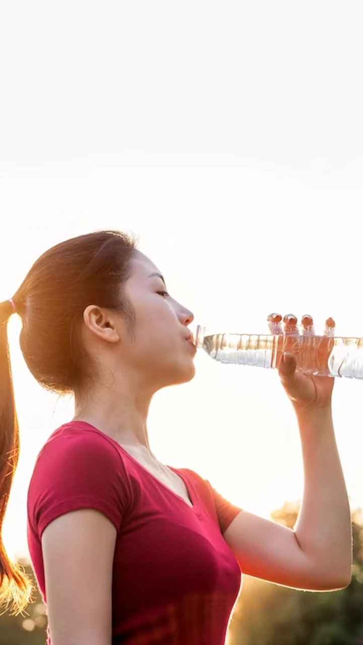 girl wearing red top and drinking water front of the sun light